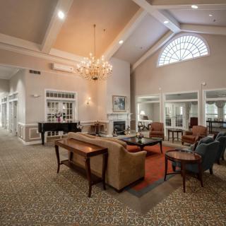 A spacious and elegantly designed living room with a high ceiling, large chandelier, and comfortable seating arrangement.