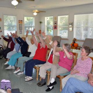 A group of elderly people participating in a seated exercise session at a community center.