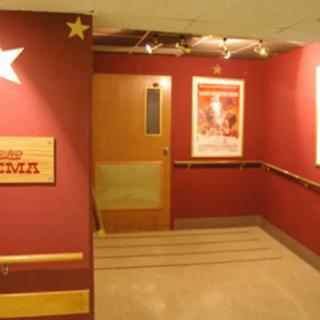 A hallway with red walls, adorned with star decorations and posters, leading to a wooden door.