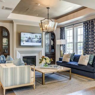 A stylishly designed living room featuring a comfortable seating area, elegant chandelier, and a cozy fireplace.
