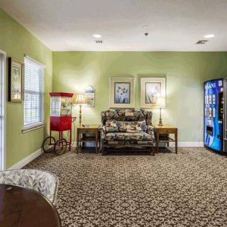 A cozy lobby area with patterned carpet, a floral couch, a popcorn machine, and a vending machine.