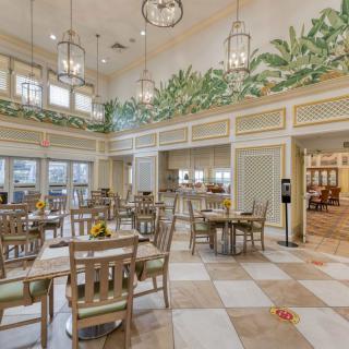 A beautifully decorated dining area with wooden tables and chairs, adorned with hanging lights and greenery.