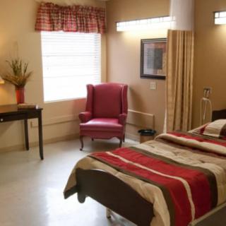 A cozy and well-lit bedroom with a comfortable bed, red armchair, and soft lighting.
