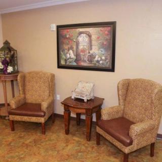 A cozy seating area with two upholstered chairs, a table, and a decorative painting on the wall.