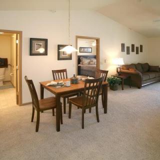 A cozy living and dining area with a wooden table, chairs, and a comfortable sofa.