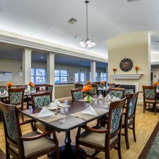 A cozy dining room setup with elegantly arranged tables and chairs, featuring warm lighting and decorative elements.