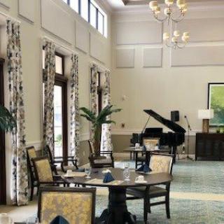 Elegant dining area with a grand piano and large windows.