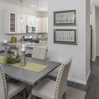 Modern dining area with a view into the kitchen, featuring elegant furnishings and contemporary decor.