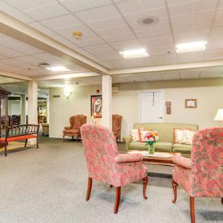 A cozy seating area with armchairs and a sofa in a warmly lit room.