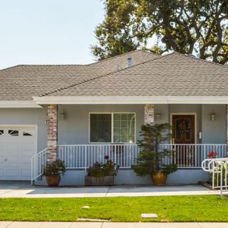 A cozy single-story house with a small porch and neatly maintained front yard.