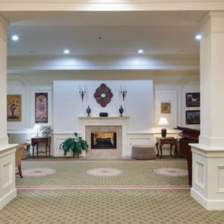 A well-decorated lobby area featuring a central fireplace, surrounded by elegant furniture and soft lighting.