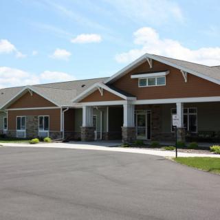 A single-story residential building with a modern architectural design set against a partly cloudy sky.