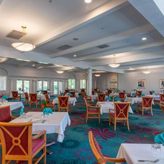 A spacious and elegantly decorated dining room with multiple tables and chairs, featuring a calming ambiance.