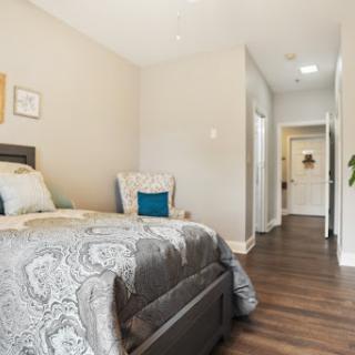 A cozy and modern bedroom featuring a neatly made bed, stylish decor, and warm wooden flooring.