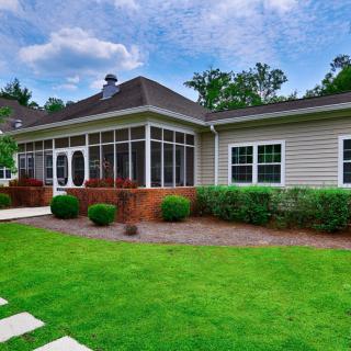 A beautiful backyard with a well-maintained lawn and a cozy screened porch.