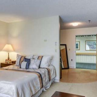 A cozy bedroom interior with a neatly made bed, side lamp, and a freestanding mirror.