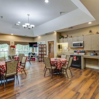 A modern kitchen and dining area with hardwood floors, featuring tables and chairs set for dining.