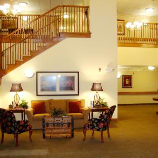 A well-lit lobby featuring comfortable seating and wooden stairs.
