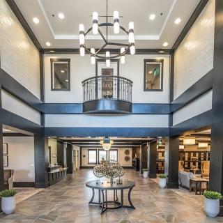 A spacious and elegantly designed lobby with a modern chandelier, featuring a central table and seating area.