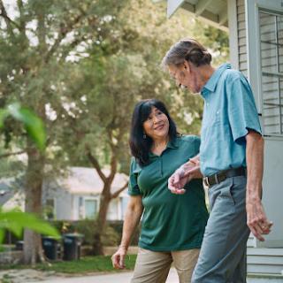 A friendly conversation between two individuals as they stroll together in a sunny outdoor setting.