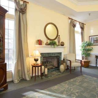 A traditional living room with a fireplace, elegant curtains, and classic furniture.