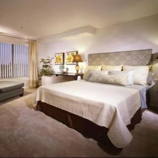 A modern, cozy bedroom featuring a large bed with decorative pillows, nightstands with lamps, and framed artwork above the headboard.