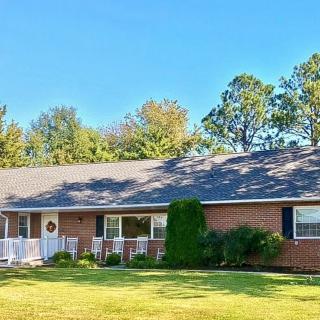 A single-story ranch-style brick house with a well-maintained front yard and trees in the background.