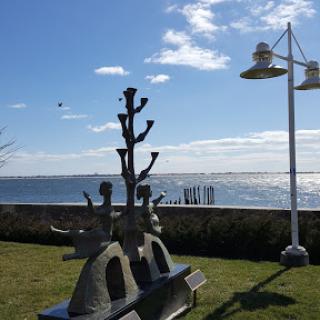 A beautiful sculpture by the waterfront under a clear blue sky.