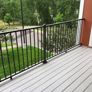 A balcony with a metal railing overlooking a green outdoor area.