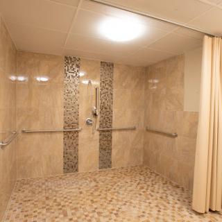 A spacious and elegantly designed shower area featuring textured tiles and grab bars for accessibility.