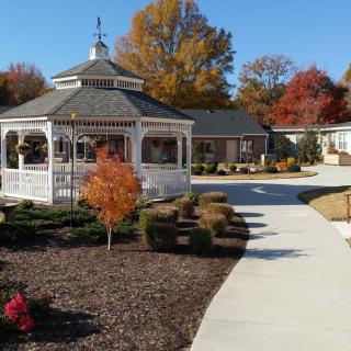 A charming gazebo in an autumnal setting with vibrant foliage and a well-maintained pathway.