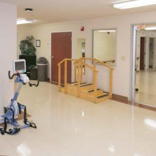 A clean and organized rehabilitation room with exercise equipment and therapy stairs.