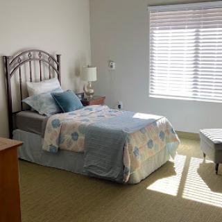 A cozy and well-lit bedroom featuring a neatly made bed and minimalistic decor.
