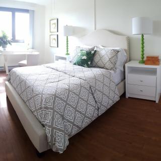 A cozy bedroom with a neatly made bed, nightstands, and lamps by the window.