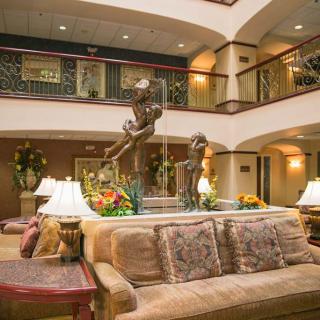 A luxurious hotel lobby featuring comfortable seating, elegant decor, and a central fountain.
