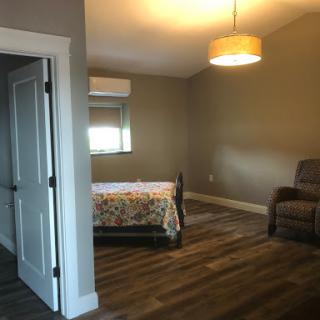 A cozy, well-lit bedroom featuring a bed with a floral blanket and a comfortable recliner.