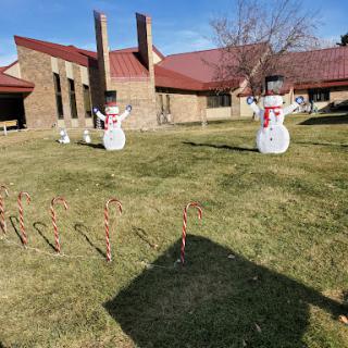 A festive display featuring snowmen and candy canes set against a sunny backdrop.