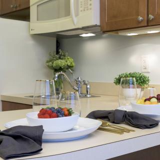 A modern kitchen countertop with a stylish dining setup, featuring fresh fruits and decorative plants.