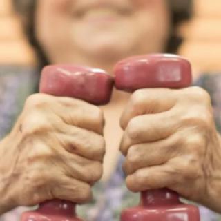 An elderly person holding pink dumbbells, focusing on fitness and exercise.