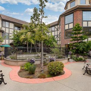 A peaceful courtyard surrounded by a multi-story building with well-maintained landscaping and benches.