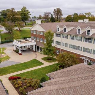Aerial view of a multi-story building with landscaped lawns and trees surrounding it.