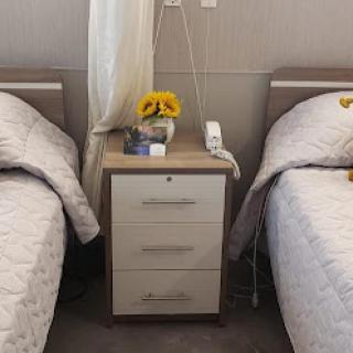 A serene bedroom featuring twin beds with a stylish nightstand adorned with colorful flowers.