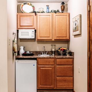 A compact kitchen area with wooden cabinets, a mini fridge, and a microwave.