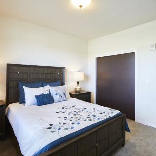 A neatly arranged bedroom with a bed, nightstand, and lamp.
