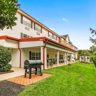 A spacious backyard with a patio and barbecue grill, featuring a well-maintained lawn and outdoor seating.