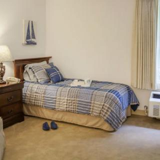 A cozy bedroom with a single bed, nightstand, and a lamp.