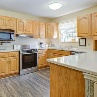 A well-lit and modern kitchen with wooden cabinets and stainless steel appliances.