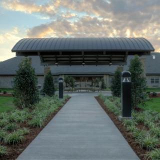 A scenic view of a modern barn-style building with a landscaped pathway leading to the entrance.