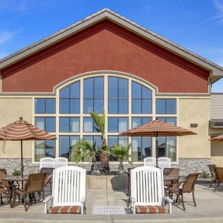 A building with large windows and outdoor seating featuring chairs, tables, and umbrellas.