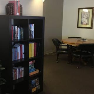 A cozy reading nook with a bookshelf filled with books and a workspace featuring a table and chairs.